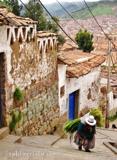 Woman carryies a sheaf of grass up a hill, Cusco, Peru photo