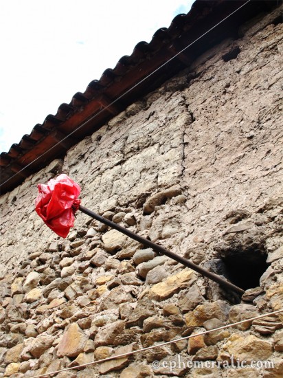 Red bag on a pole, the sign of chicha de jora nearby, Ollantaytambo, Peru